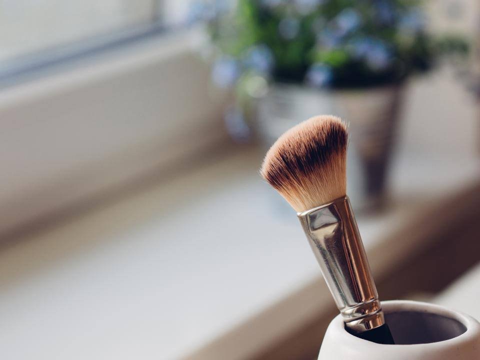 A makeup brush in a pot by a window