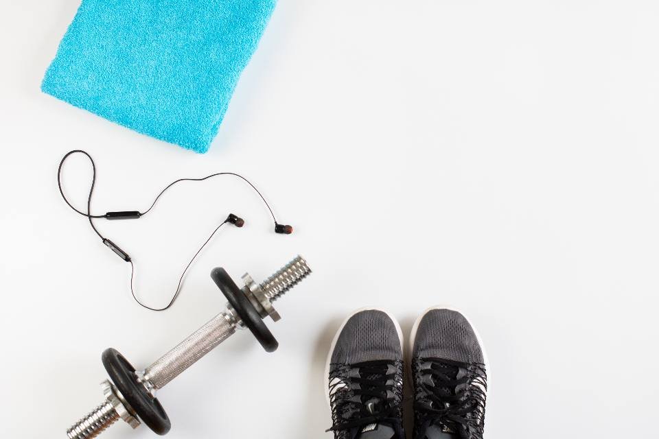 A towel, dumbbell and trainers laid out on white