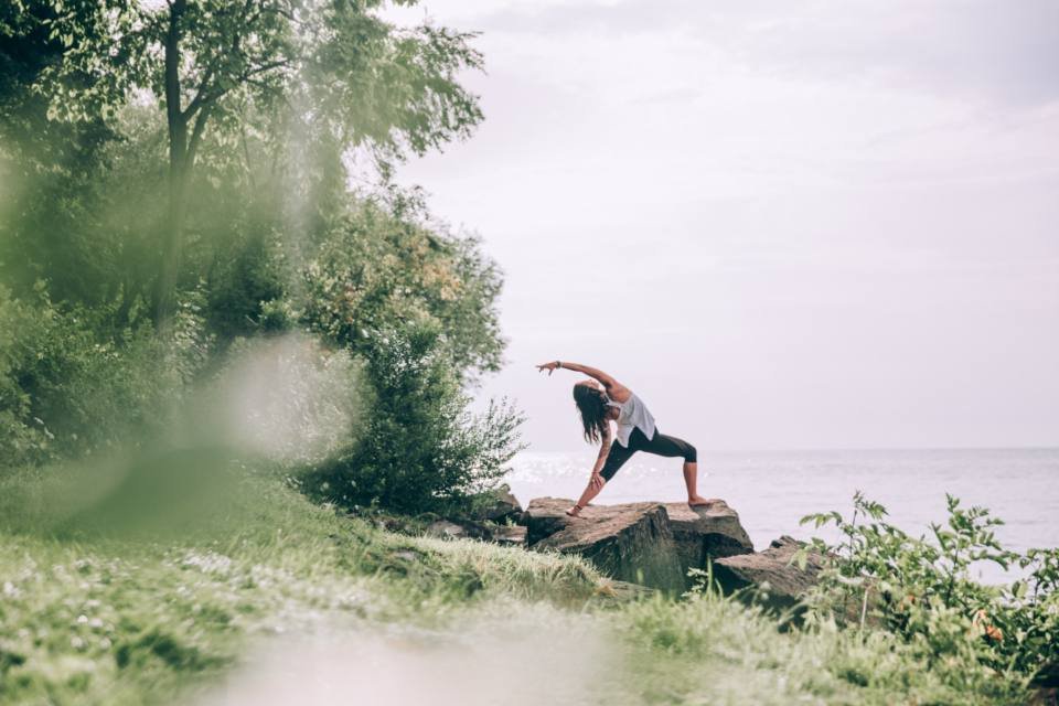 A person doing a yoga pose in a green landscape
