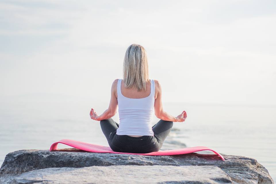 A person meditating on a rock by the sea