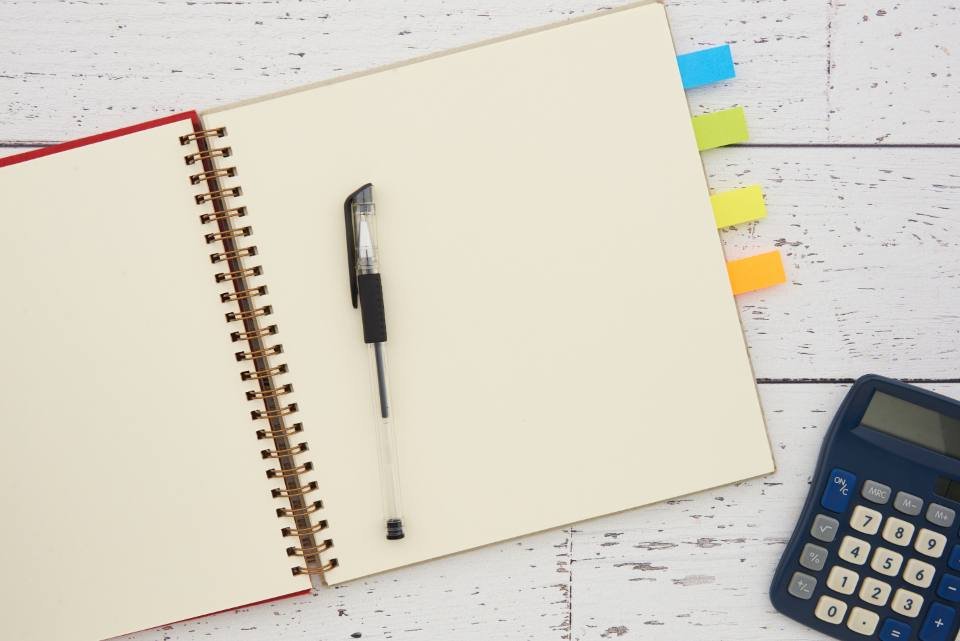 An open notebook with a pen and calculator