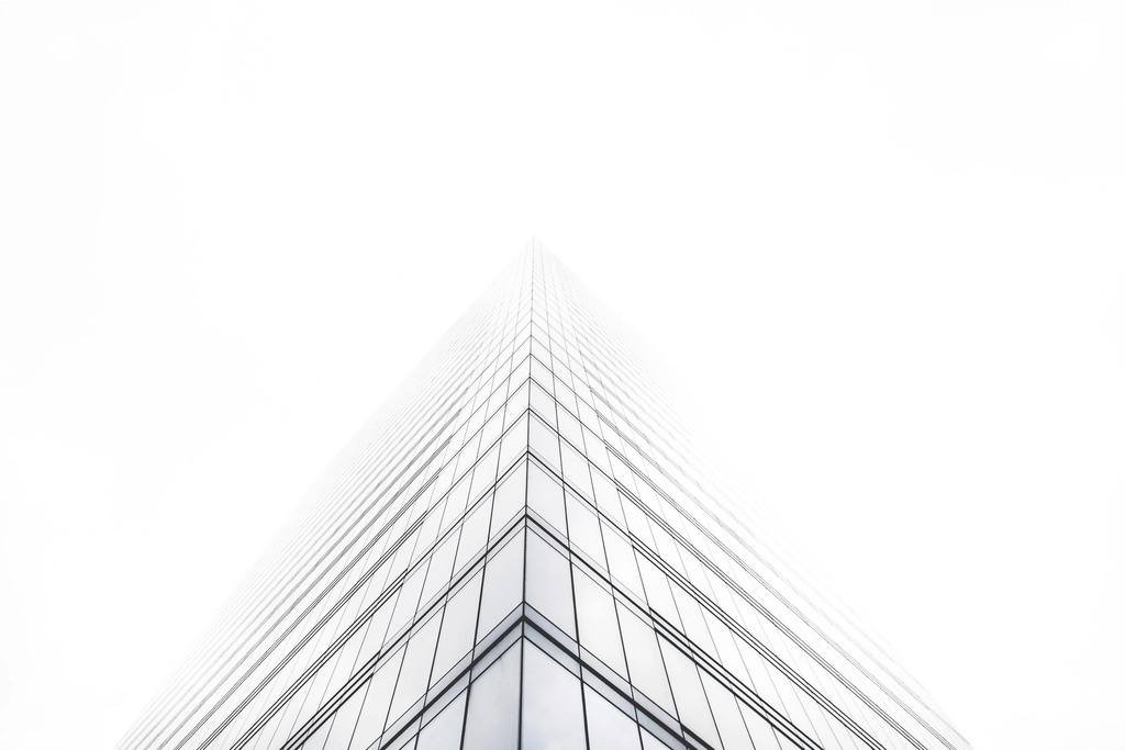 A tall glass building fading into white sky