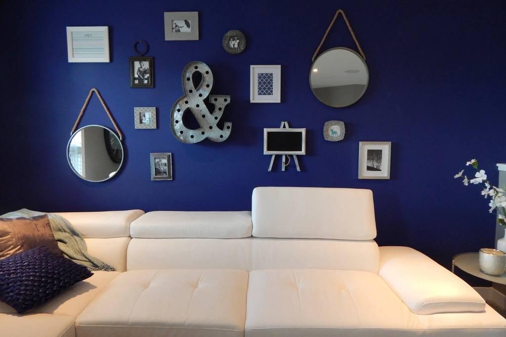 A living room with a navy feature wall and white sofa