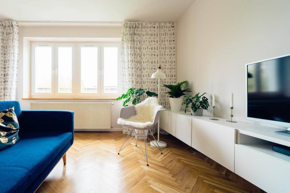 A living room with parquet floor and blue sofa