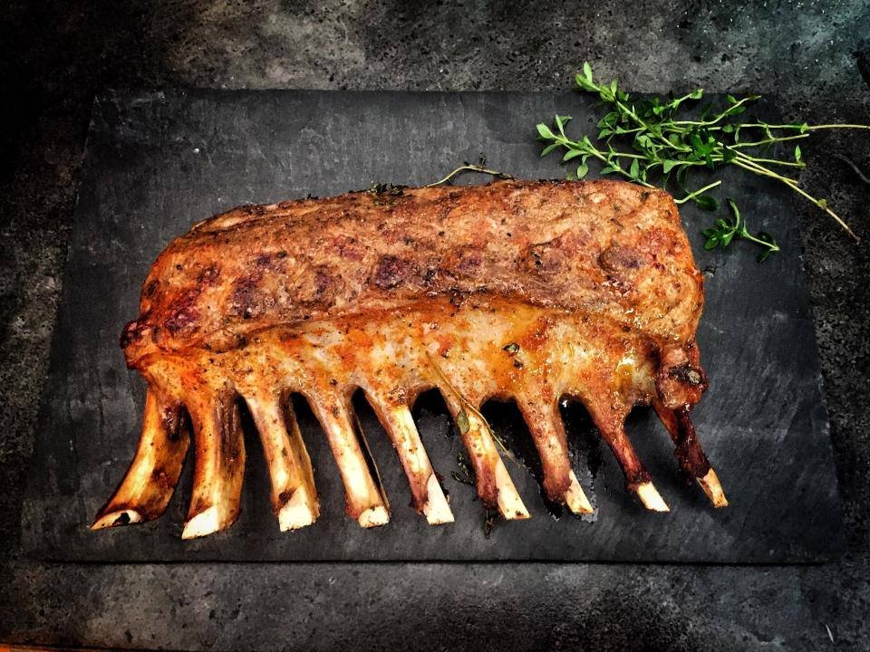 A rack of lamb on a dark serving board