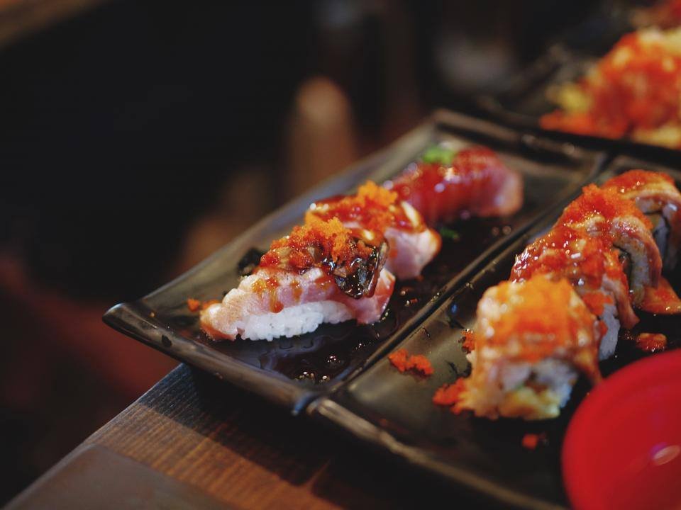 Plates of nigiri sushi on a dark table